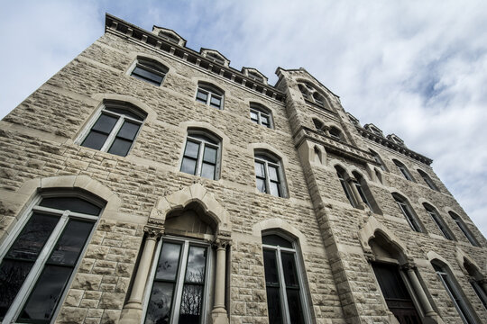 View of a historic stone building with gothic-style arched windows and intricate masonry under a cloudy sky in Lincoln, Nebraska, United States.
