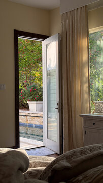 Open door revealing pool area from cozy bedroom interior