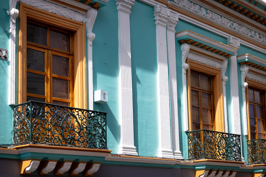 View of the colorful colonial facade in the Historic Center of Quito featuring teal walls, white pilasters, and ornate wrought-iron balconies in Quito, Pichincha, Ecuador.