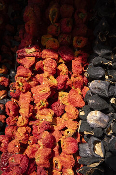 View of strings of dried red peppers and dark eggplants hanging in a traditional market stall Kayseri, Kayseri, Turkiye.