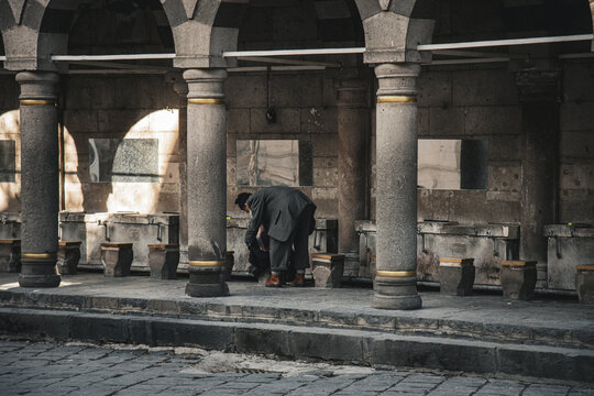 View of a man in a suit at a traditional stone ablution station with arches and columns in Kayseri, Kayseri, Turkiye.