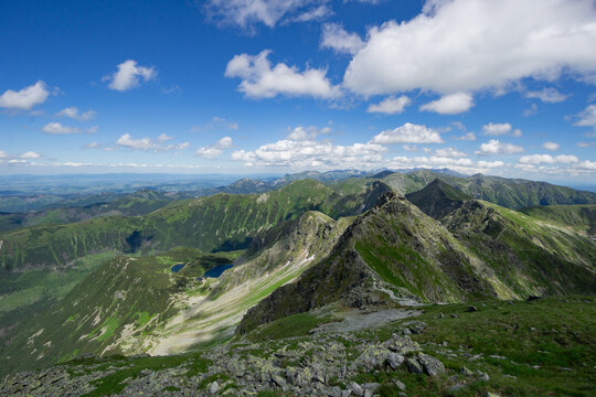 View of Tri kopy in Western Tatras with rocky ridges, green slopes, and mountain lakes under a blue sky with white clouds in Ziar, Zilina Region, Slovakia.