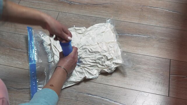 Person Efficiently Vacuum Packing Clothes for Travel with Pump