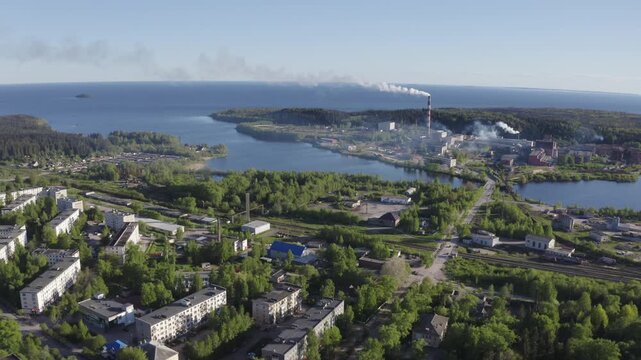 Forward reveal aerial shot of Pitkyaranta town and cellulose factory on sunny summer day. Karelia, Russia.