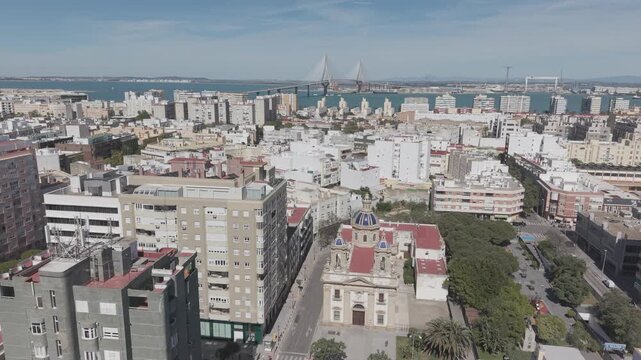Aerial view of San Jose Church in Cadiz, Spain. Cinematic drone shot of the historic Neoclassical parish and surrounding city streets on a sunny day.