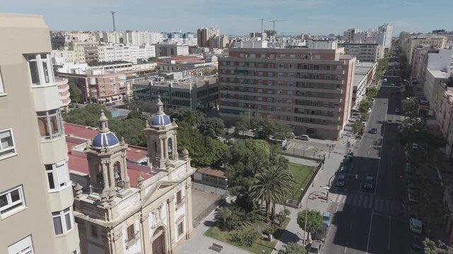 Aerial view of San Jose Church in Cadiz, Spain. Cinematic drone shot of the historic Neoclassical parish and surrounding city streets on a sunny day.