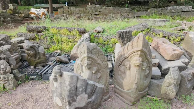 Ancient stone carvings, including figures and mythical creatures, lie scattered at the Angkor Wat temple complex in Siem Reap, Cambodia. These artifacts are part of the historical ruins.