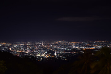 Fototapeta premium Wide night cityscape glowing urban lights viewed from mountain overlooking roads neighborhoods illuminated skyline