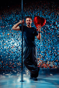 Man holding heart balloon by dance pole