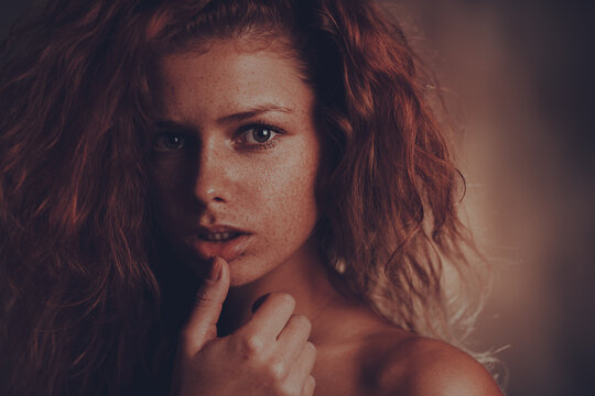 Dramatic portrait of beautiful young redhead woman with natural freckles