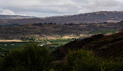 Obraz premium central otago new zealand schist rock formations mountains hills cliffs textures rugged with lake river background landscape nature scenic
