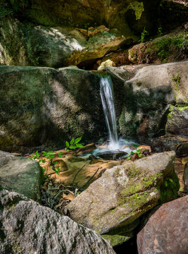 View of a small waterfall at Pickle Springs Natural Area flowing over mossy sandstone boulders into a clear pool in New Offenburg, Missouri, United States.