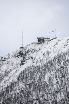 View of the Fjellheisen cable car upper station on the snowy slopes of Mount Storsteinen with a communication tower and construction crane Tromso, Troms, Norway.