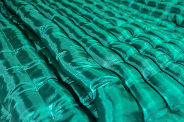 Fototapeta premium close-up of a green floor mattress with soft, textured, wavy fabric and a glossy sheen