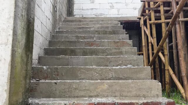 Unfinished concrete stairs at a building construction site during heavy rainfall.