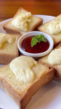 Close-up vertical video of crispy cheesy garlic bread served with dipping sauce in a cozy cafe setting. Warm comfort food aesthetic with melted cheese, golden toast, and delicious snack vibes.
