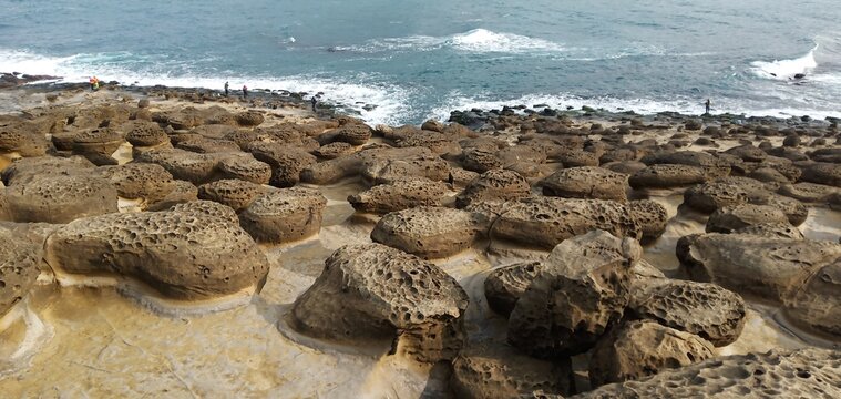 Unique honeycomb rock formations on a coastal shore with ocean waves