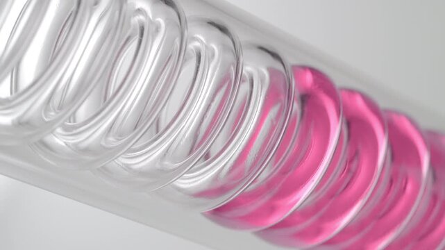 Extreme close of pale pink clear liquid flowing through the spiral of an inclined coil laboratory condenser, filling it up on grey background | Strawberry distillate cosmetic extract concept