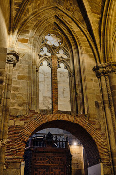 Plasencia, Spain - 03 December 2025: View of Catedral Nueva de Plasencia showing the intricate Gothic stone arches, a large tracery window, and historic brickwork details inside.