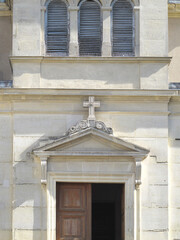 Classical French Church Entrance with Stone Pediment, Cross and Wooden Door © Maroun Rached