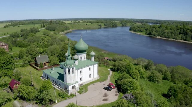 Forward reveal aerial shot of John the Baptist cathedral (1695) and Volkhov river on sunny summer day. Staraya Ladoga, Leningrad Oblast, Russia.