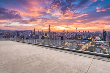 Fototapeta premium Empty concrete rooftop terrace overlooking a modern city skyline at colorful sunset