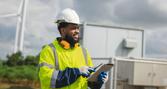 Worker inspects wind farm equipment with clipboard