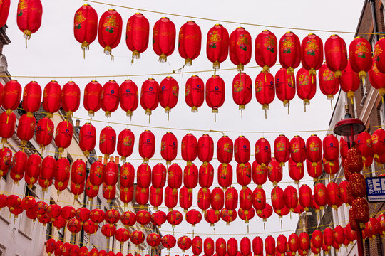 London, United Kingdom - 12 May 2025: View of red Chinese lanterns hanging in rows across a street in Chinatown under an overcast sky.