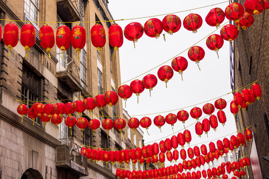 London, United Kingdom - 12 May 2025: View of red Chinese lanterns hanging in rows across a street in Chinatown against historic brick buildings.