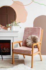 Fototapeta premium Interior of stylish living room with blooming branches in vases, fireplace and armchair