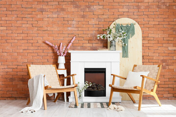 Fototapeta premium Interior of living room with fireplace, armchairs and blooming branches in vases