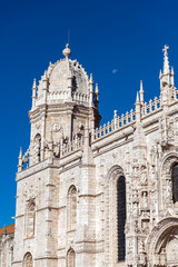 Obraz premium Lisbon, Portugal - October 11, 2025 - Close-up detail of the intricate Manueline style architecture and spires of the Jeronimos Monastery against a blue sky with the moon.