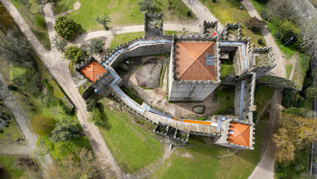 Aerial view of Guimaraes Castle featuring its medieval stone fortifications, crenelated towers, and surrounding green parkland under soft daylight in Guimaraes, Braga, Portugal.