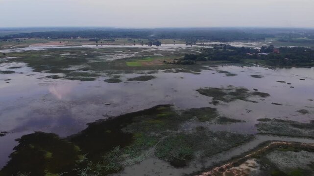 Aerial view of the Huay Saneng reservoir area with green algae on the water surface and lush vegetation in Surin, Thailand.