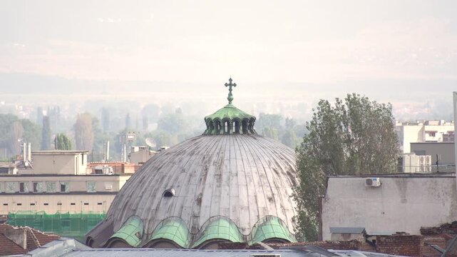 Above the rooftops of Sofia, Bulgaria. The dome of the Church of St Paraskeva with a cross on its top. In the background view of Sofia Valley.