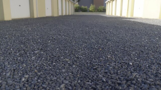 Low angle view of gravel driveway between rows of garages in a residential area