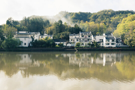 The mountains beside the river are shrouded in mist.