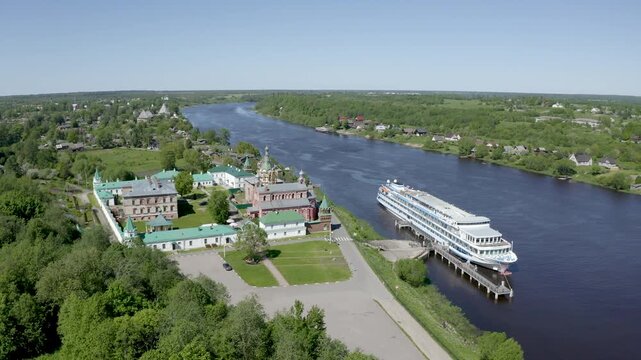 Orbital aerial footage of Nikolsky monastery and cruise ship on Volkhov river on sunny summer day. Staraya Ladoga, Russia.