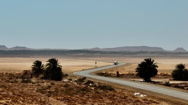 Aerial drone perspective of the asphalt road crossing the vast Chott el Djerid salt lake. Scenic desert landscape with crystalline salt flats and arid horizons in southern Tunisia