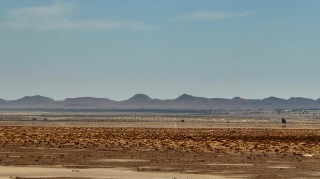 Wide drone shot of the Chott el Djerid salt flats with mountain peaks in the background. Crystalline salt crust and arid desert environment in southern Tunisia
