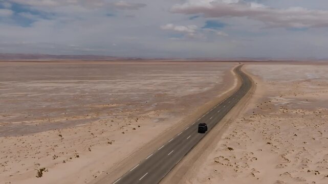 Aerial drone view of an off-road track cutting across the immense dry surface of Chott el Djerid salt lake. Crystalline salt flats and vast desert horizon in southern Tunisia
