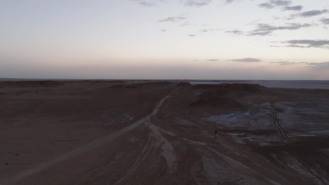 High aerial drone view of the unique Ong Jmal rock formation at sunset. Cinematic landscape overlooking the vast desert plains and salt flats of southern Tunisia.