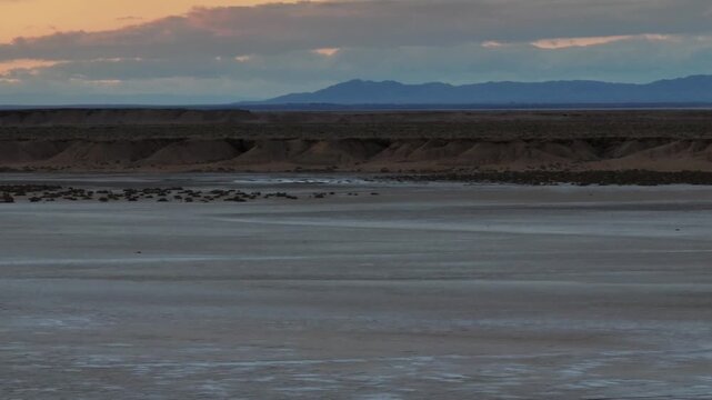Cinematic drone panorama of the famous Ong Jmal rock formation and surrounding salt flats at sunset. Dramatic desert landscape and twilight sky in southern Tunisia, North Africa