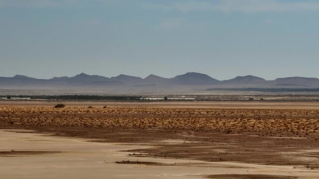 Panoramic drone shot of Chott el Djerid salt lake with the rugged Atlas Mountains on the horizon. Crystalline salt flats and desert terrain under clear sky in southern Tunisia North Africa expedition