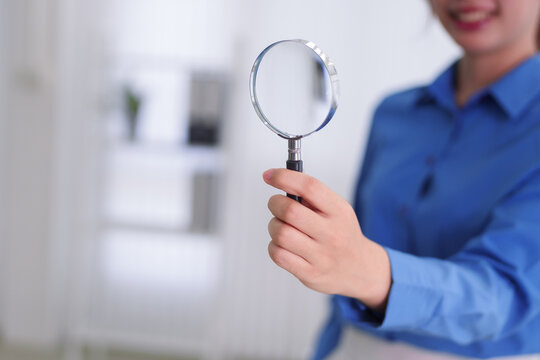 Asian business women holding magnifying glass search analysis research investigate inspect examine data information detail discovery office workplace