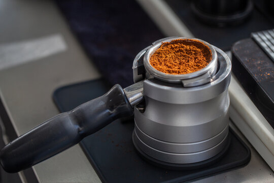 Freshly ground coffee in portafilter on professional dosing stand.