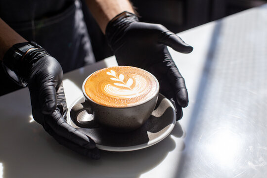 Barista serving fresh hot latte art coffee cup