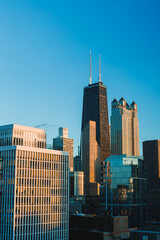 Fototapeta premium City skyline view with tall buildings under clear blue sky showcasing architectural design and urban landscape during sunset
