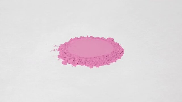 Vertical jib shot of a mountain of pink powder with a circular indentation on a soft gray backdrop, illuminated by orbiting directional light that creates shifting shadows