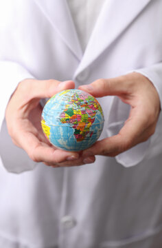 Doctor in white medical gown holding globe model